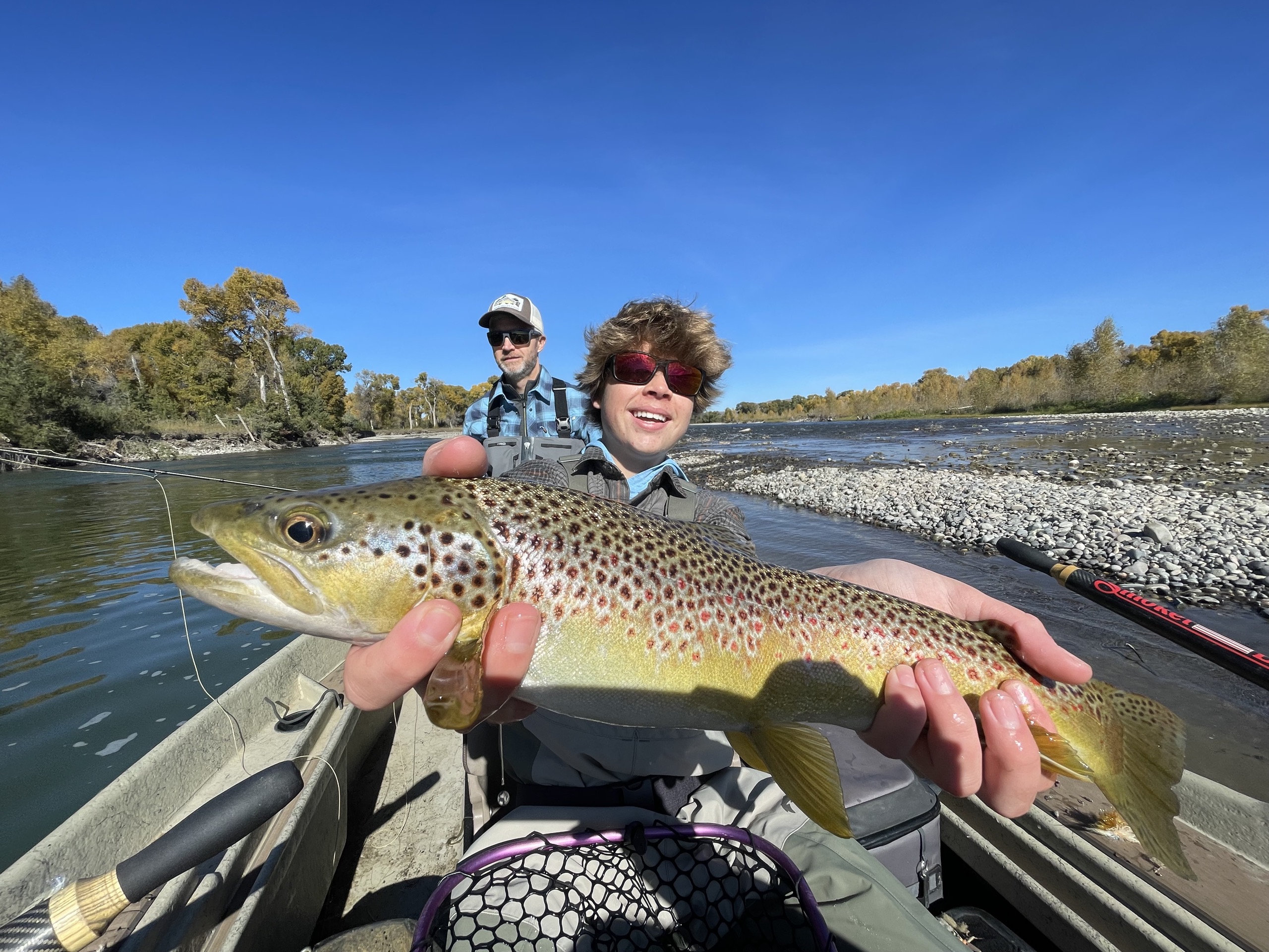 Young angler holding a trophy brown trout from a Montana drift boat