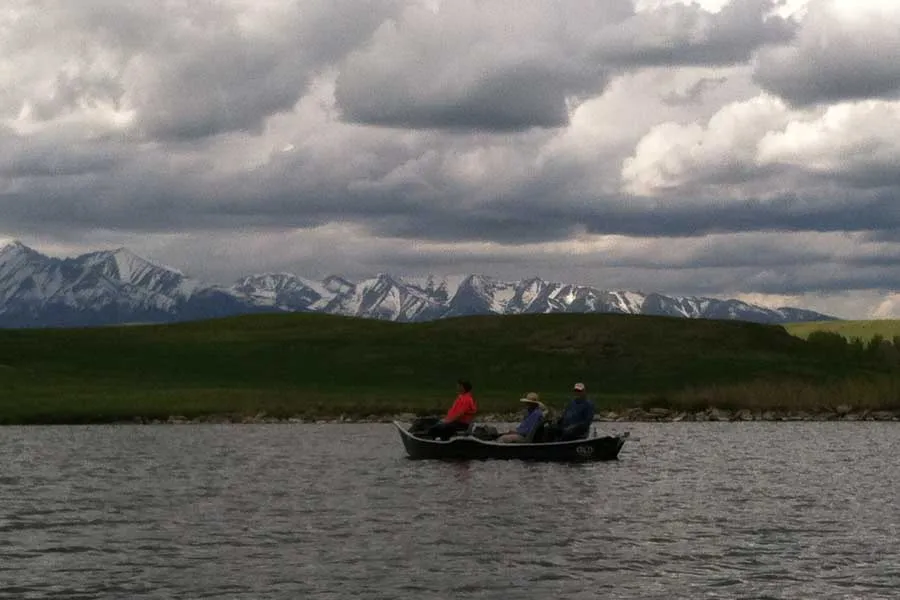 Drift boat on Burns Lake with snow-capped mountains