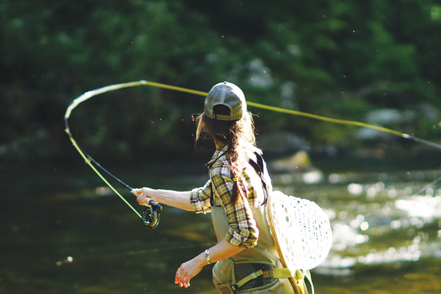 Woman fly fishing on a small Montana river in golden light
