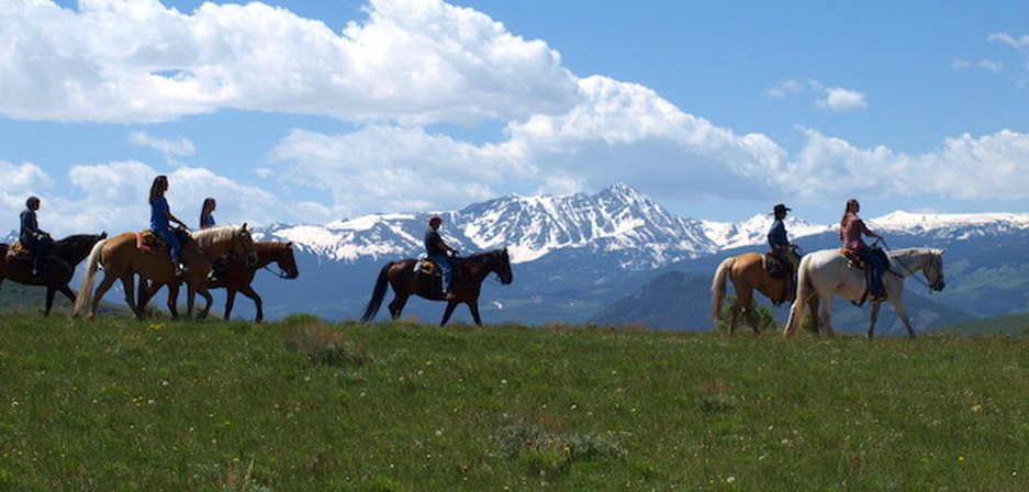 Group horseback riding with Crazy Mountain panorama
