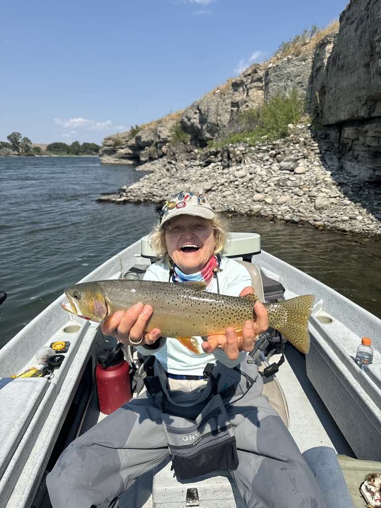 Happy angler with brown trout in the drift boat