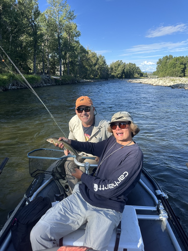 Couple with trout in the drift boat on a sunny day