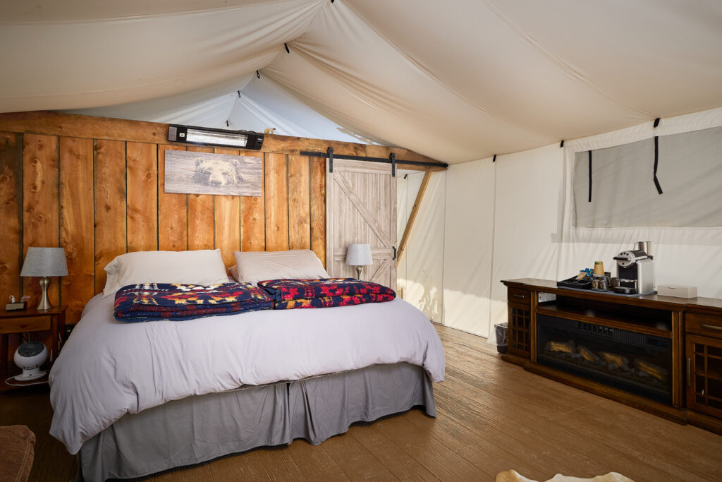 Sliding barn door and a bear print above the bed, with patterned throws at the foot and a coffee station on the console