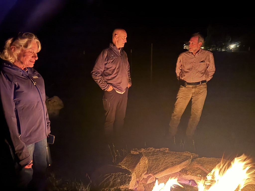 Guests gathered around the fire pit at night in warm firelight